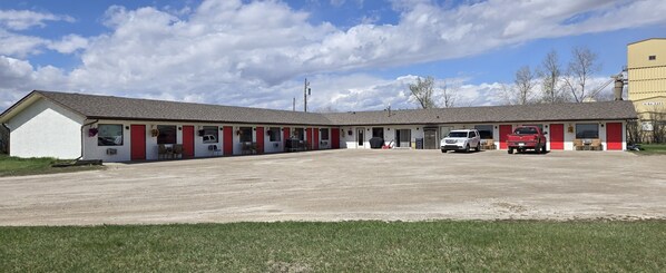 A motel with a central parking area and multiple rooms with red accents. - BLUE HORSE MOTEL (Beiseker)
