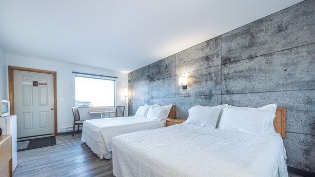 Une chambre d’hôtel avec deux lits, un bureau et une vue sur l’extérieur.