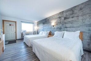 Habitación de hotel con dos camas, un escritorio y vistas al exterior.