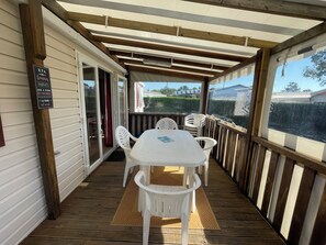 A covered outdoor area with a table and chairs, a wooden deck, and a view of the surrounding landscape.