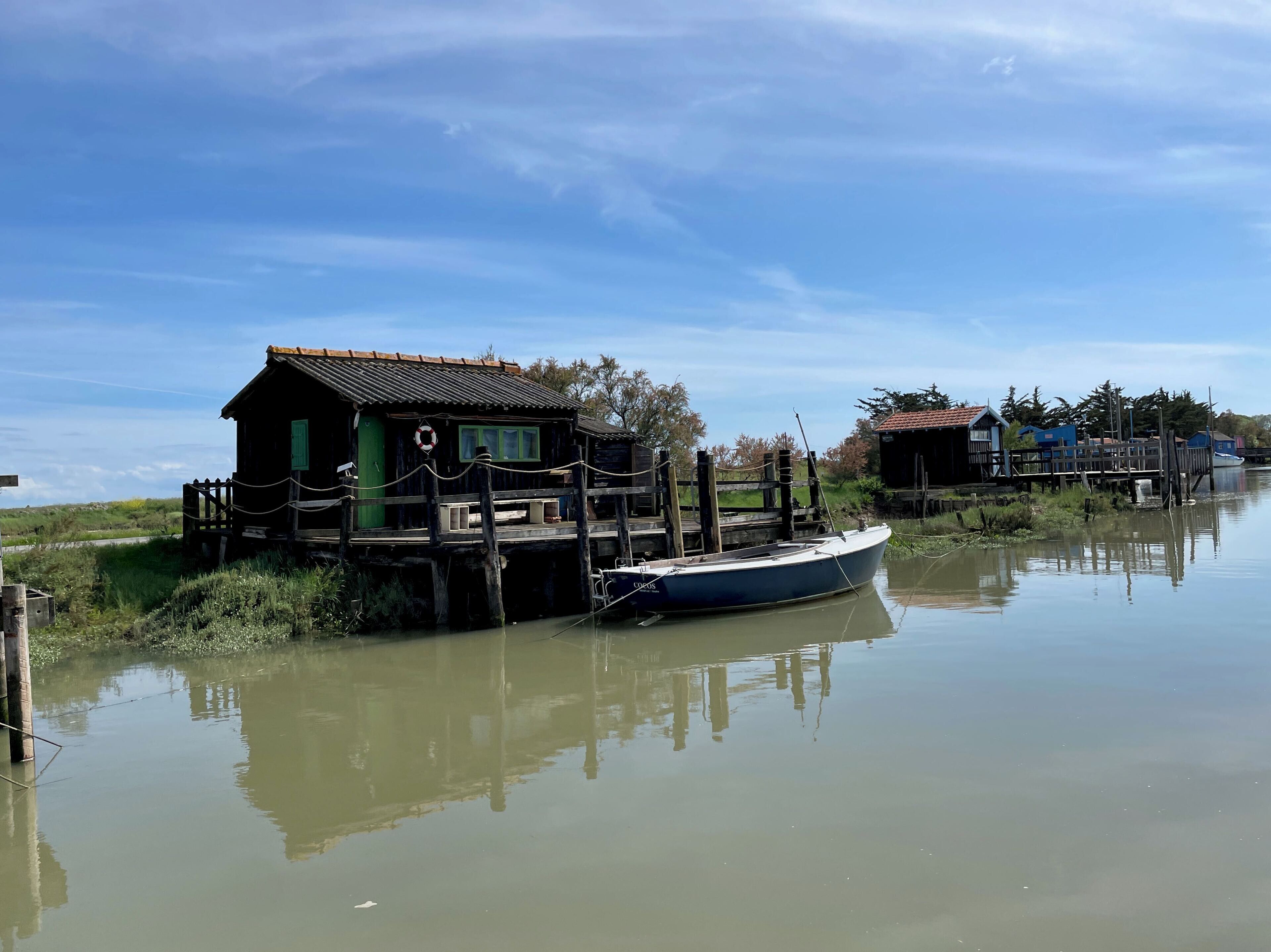 Una casa galleggiante in legno ormeggiata in acque calme sotto un cielo sereno.