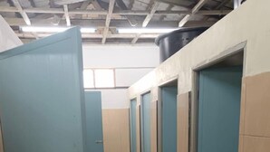 Ein Korridor mit blauen Türen, die jeweils zu einem Zimmer führen. Der Korridor besitzt einen gefliesten Boden und eine hohe Decke mit sichtbaren Balken.