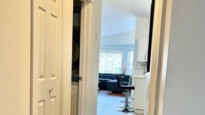 A hallway with wooden flooring leading to a living area with a couch and a dining table. - Fort McMurray Home - 4 Bedroom House: Perfect for Families & Business (Fort McMurray)