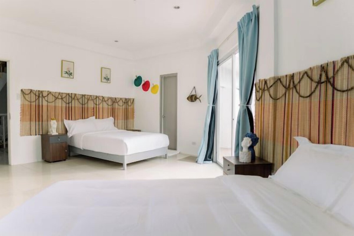 A modern bedroom with a large bed, a nightstand, a dresser, and a window with curtains.