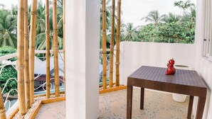 Un balcon agrémenté d’une table et d’un objet décoratif, entouré de bambous et de palmiers.