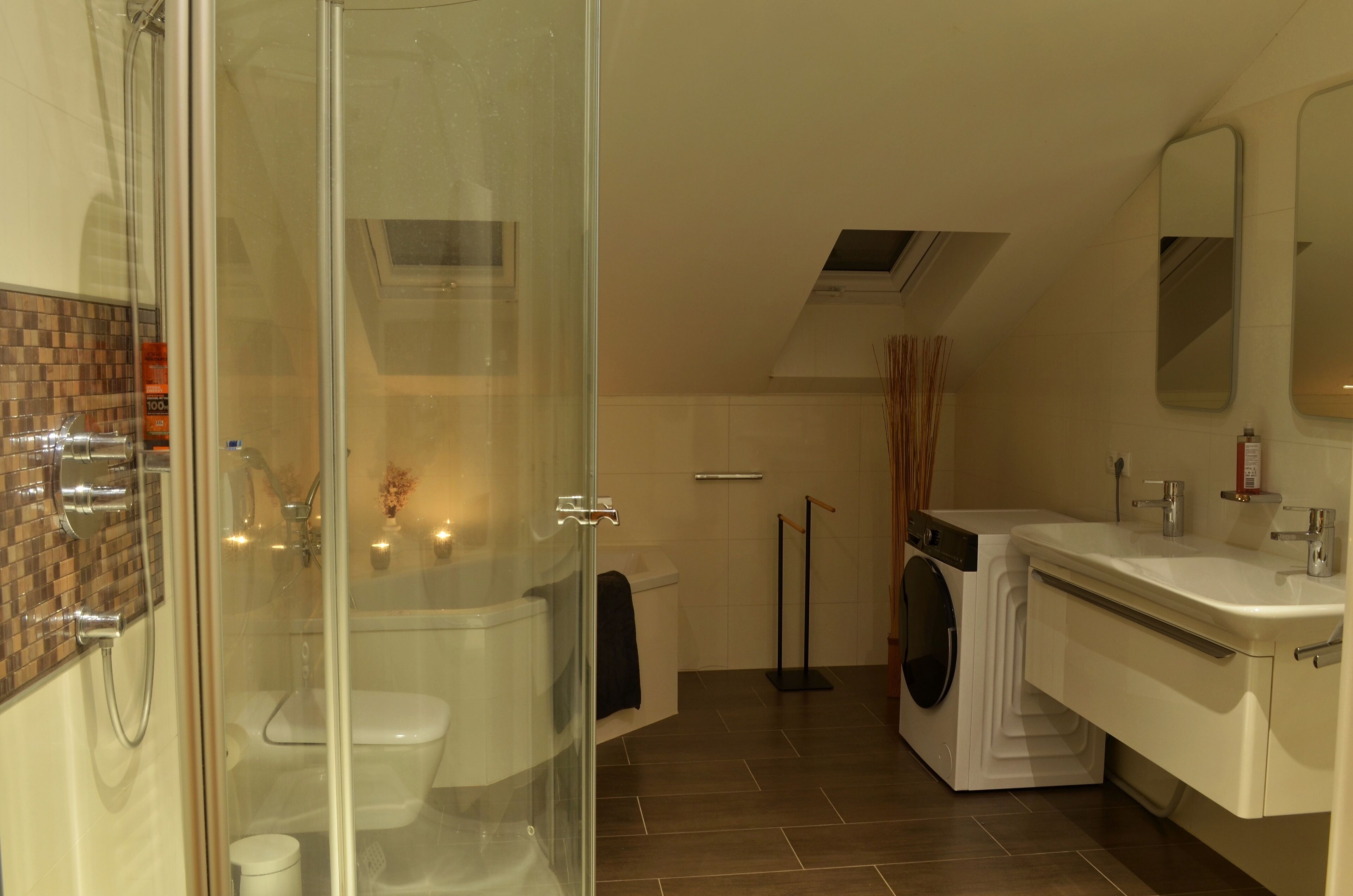 A modern bathroom with a glass shower enclosure, a toilet, a washing machine, and a sink.