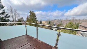 Eine Holzterrasse mit Metallgeländern, mit Blick auf ein Wohngebiet mit Häusern und Bäumen.