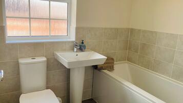 A bathroom with a toilet, sink, and bathtub.