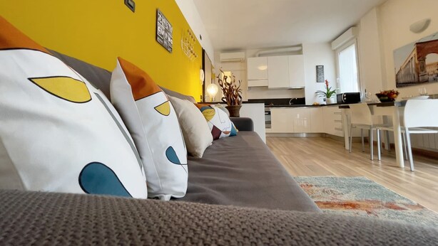 A modern living room with a sofa, a dining area, and a kitchen. - Studio With Balcony in Bovisa Milan (Milan)
