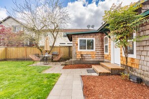 A backyard with a patio, a wooden fence, and a small tree.