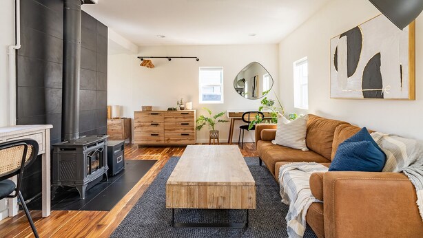 A cozy living room with a fireplace, wooden furniture, and a large mirror. - Charming Ballard Cottage Retreat with Cozy Fireplace (Seattle)