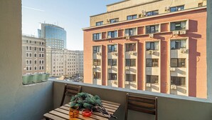 Un balcon avec une table en bois, des chaises et une branche de pin servant de décoration.