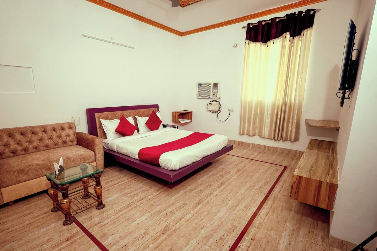 A bedroom with a bed, a sofa, a small table, and a wooden cabinet.