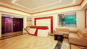 A modern lobby with a reception desk, a sofa, and a large window. - Balada Castles Hotel & Resort (Dera Bassi)