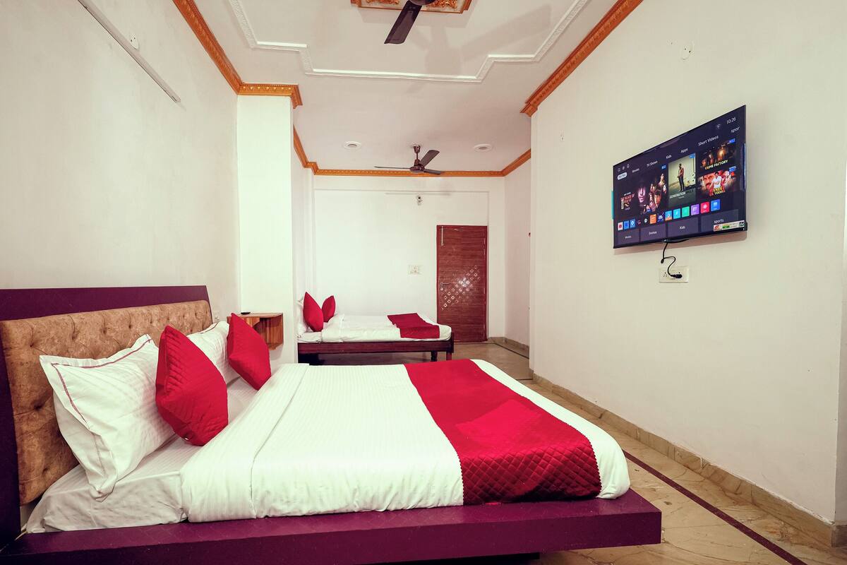 A hotel room with a large bed, a TV mounted on the wall, and a ceiling fan.