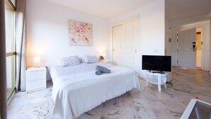 A bedroom with a bed, a TV, a painting, and a white door. - Studio in Marbella with Beachfront Pool (Marbella)