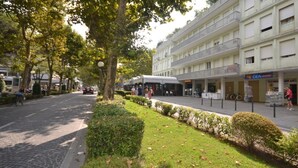 Una calle con una hilera de edificios, incluyendo un hotel con balcón y una tienda.