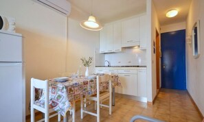 Une cuisine compacte avec des meubles blancs, un pare-feu en carrelage et un coin repas avec une table dressée pour deux personnes.