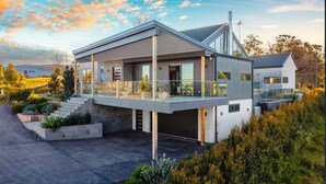 A modern two-story house with a covered outdoor area, a garage, and a landscaped driveway.