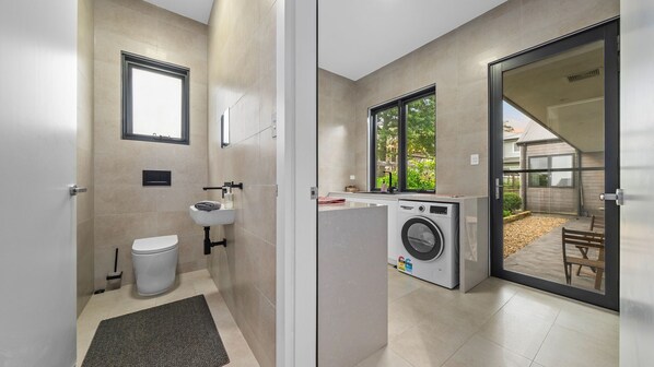 A compact, modern bathroom with a toilet, sink, and built-in washing machine.