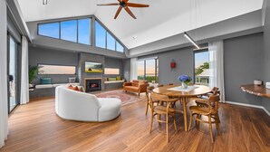 A spacious living area with a fireplace, a dining table, and a large window overlooking a scenic view.