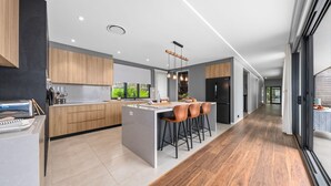 A modern kitchen with a central island, wooden cabinets, and a black refrigerator.