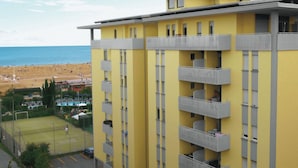 A yellow building with multiple balconies overlooking a beach and a sports field. - Bibione seaview apartment - Beahost (Bibione)