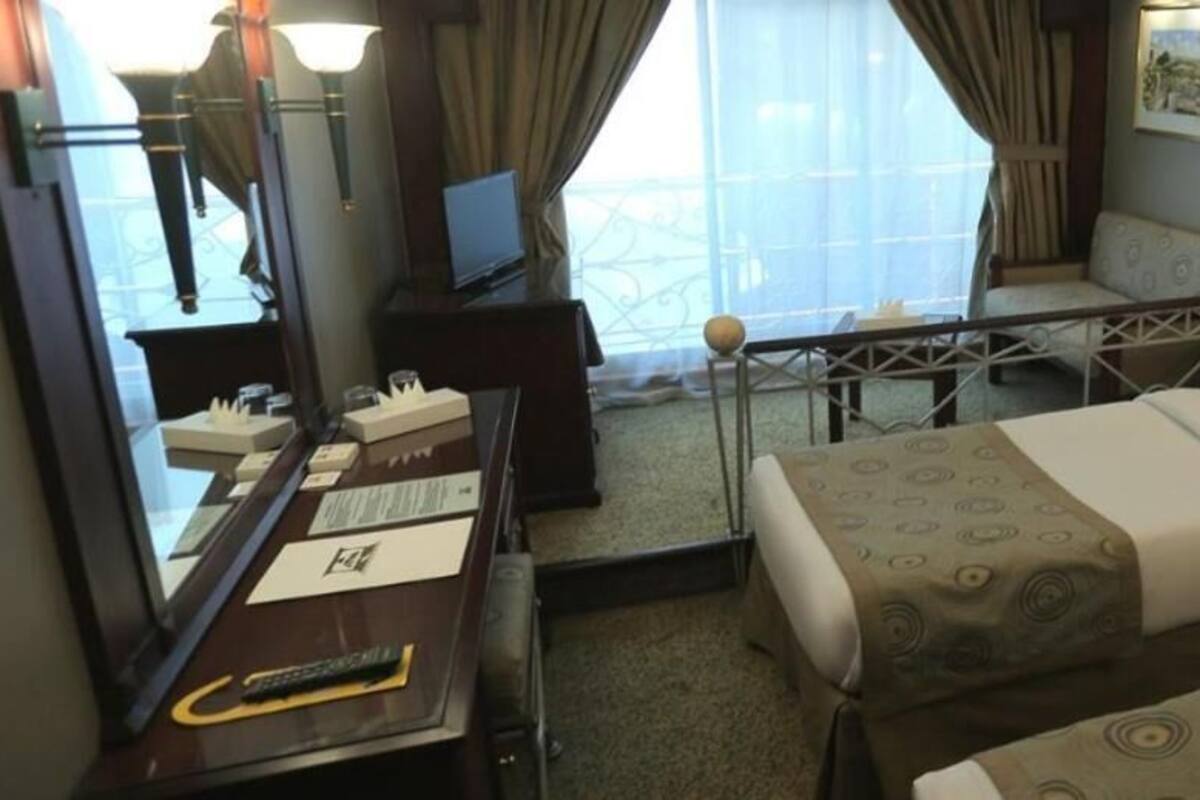 Een hotelkamer met twee bedden, een bureau, een stoel, een televisie en een balkon met uitzicht.