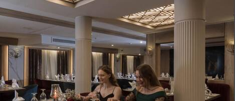 A restaurant with a geometric ceiling design, white columns, and a modern interior.