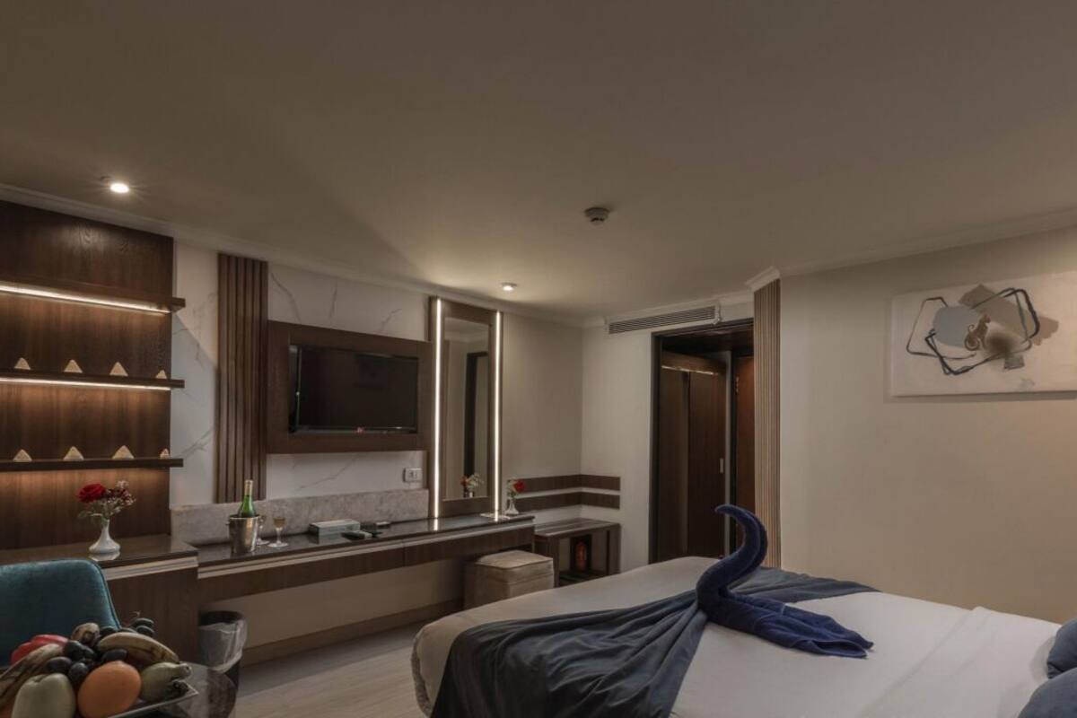 Een moderne hotelkamer met een groot bed, een kaptafel met spiegel, een ingebouwde televisie en een uniek kunstwerk aan de muur.