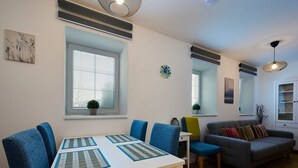 A modern living room with a dining table, blue chairs, a grey sofa, and a small side table. - Nice apartment for 4 people with WIFI and TV (Jablonec Nad Nisou)