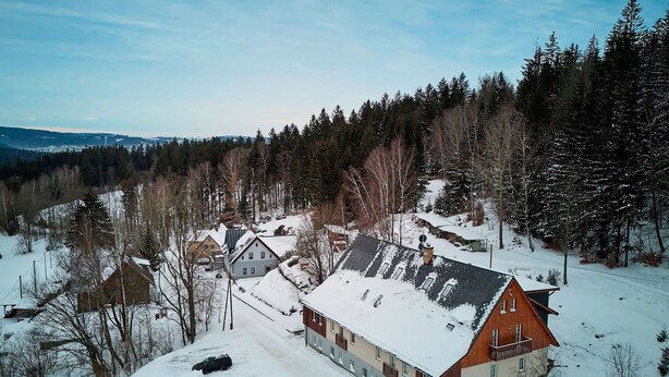 A snow-covered residential area with houses, a wooden cabin, and a forested background. - Nice apartment for 4 people with WIFI and TV (Jablonec Nad Nisou)