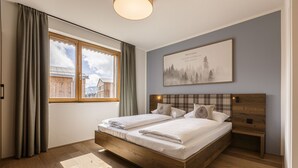 Una camera da letto con un letto in legno, una finestra con tende, una testiera con una luce e un quadro appeso al muro.