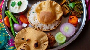 Un pasto tradizionale indiano su un piatto di metallo, con riso, pane piatto, verdure e diversi curry.