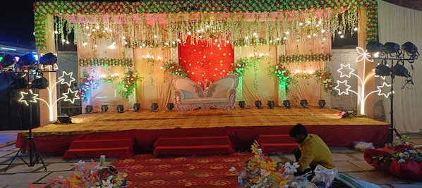 Un escenario con un fondo floral, alfombra roja y sofá blanco.