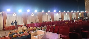 Un escenario con cortinas drapeadas y una estrella de David, rodeado de hileras de sillas rojas.