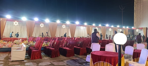 An outdoor event with rows of chairs and tables, a stage with a backdrop, and a star-shaped decoration. - HOTEL ANNAPURNA REGENCY (Mirzapur)