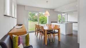 Una cucina moderna con zona pranzo, ampie finestre e vista sull'esterno.
