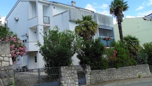 Un edificio moderno de dos pisos con un muro de piedra y una puerta metálica al frente.