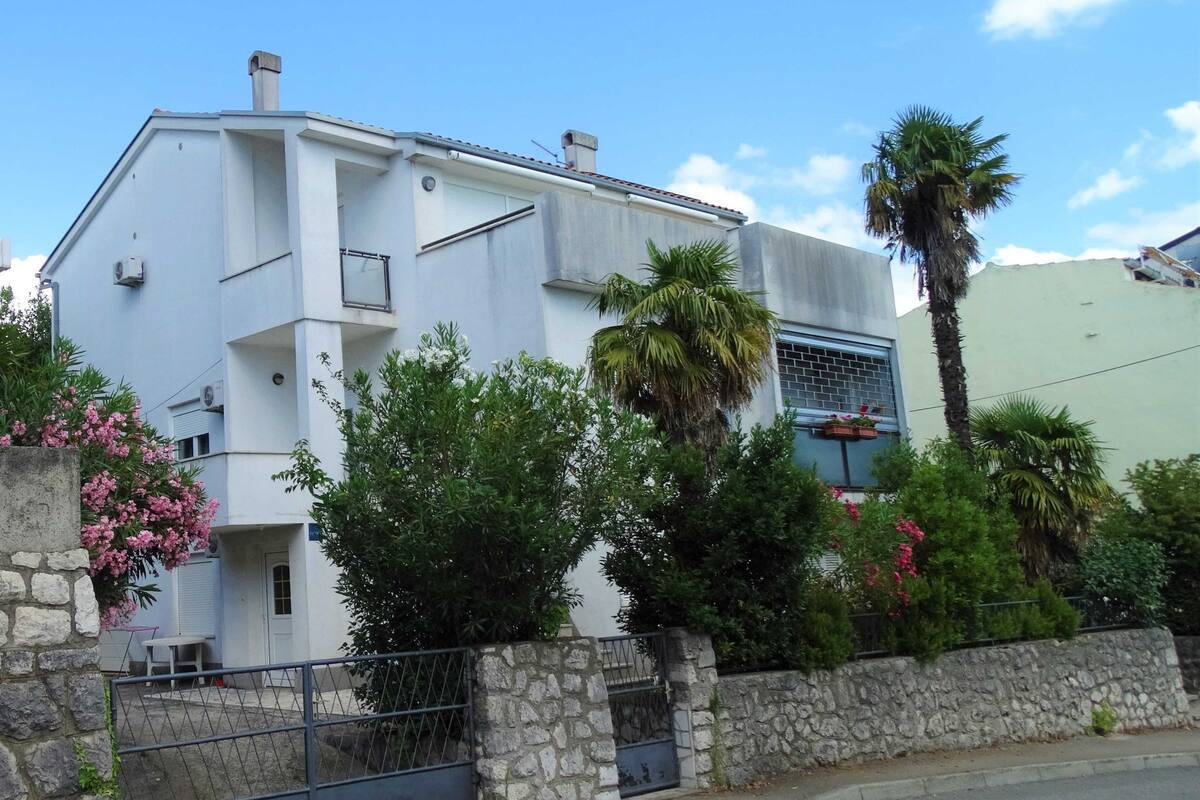 A modern two-story building with a stone wall and metal gate in front.