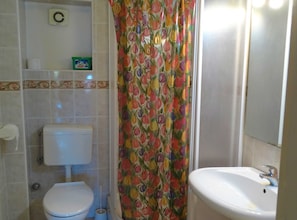 A bathroom with a toilet, a sink, and a shower curtain with a floral pattern.