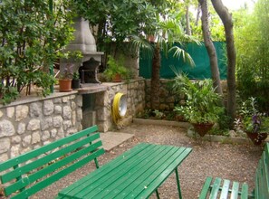 Un mur de pierre avec un banc et une table verte dans un espace aménagé en jardin.