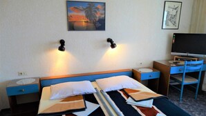 Een hotelkamer met een bed, een bureau met een televisie en twee wandlampen.