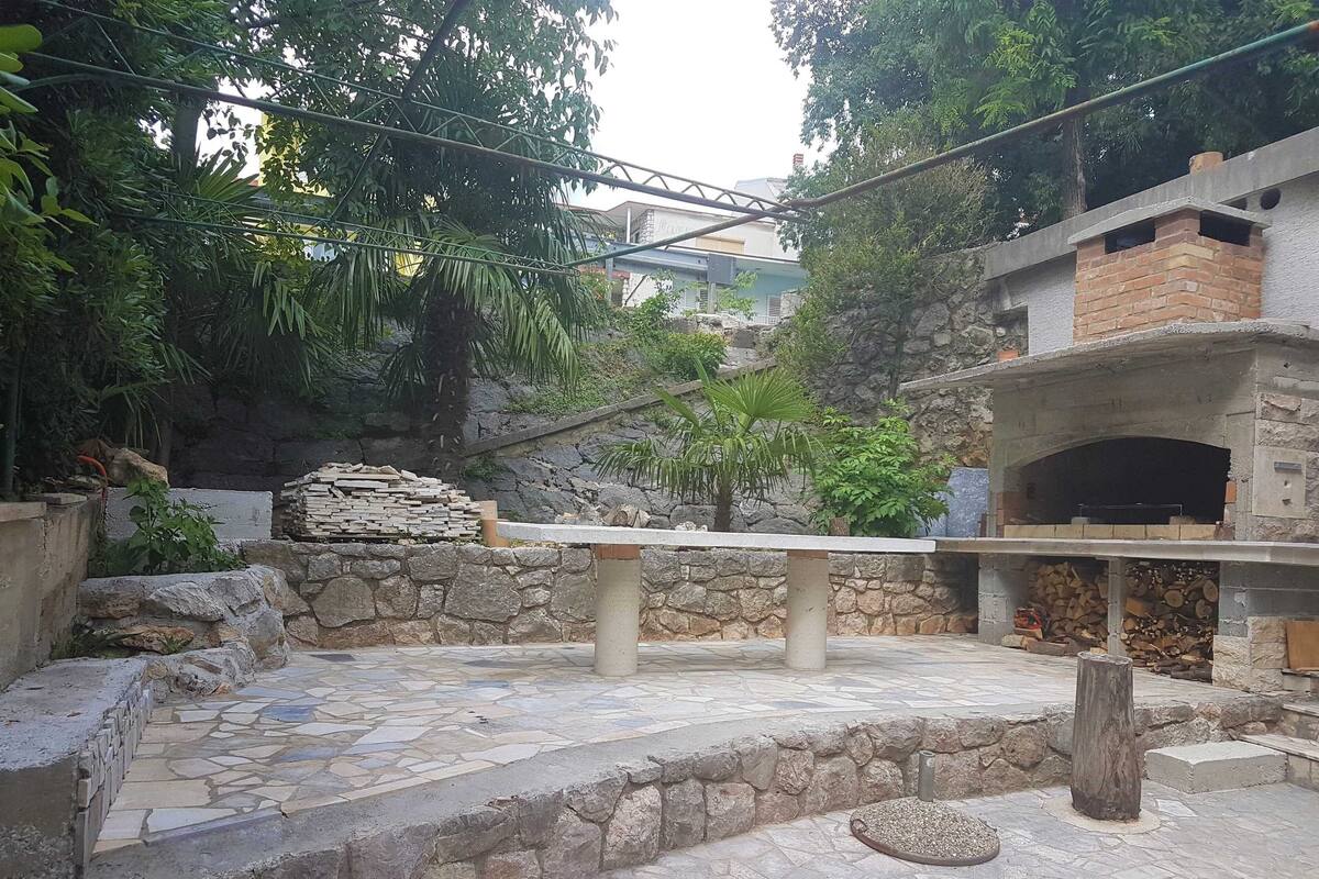 An outdoor patio area with stone flooring, a stone wall, and a brick oven.