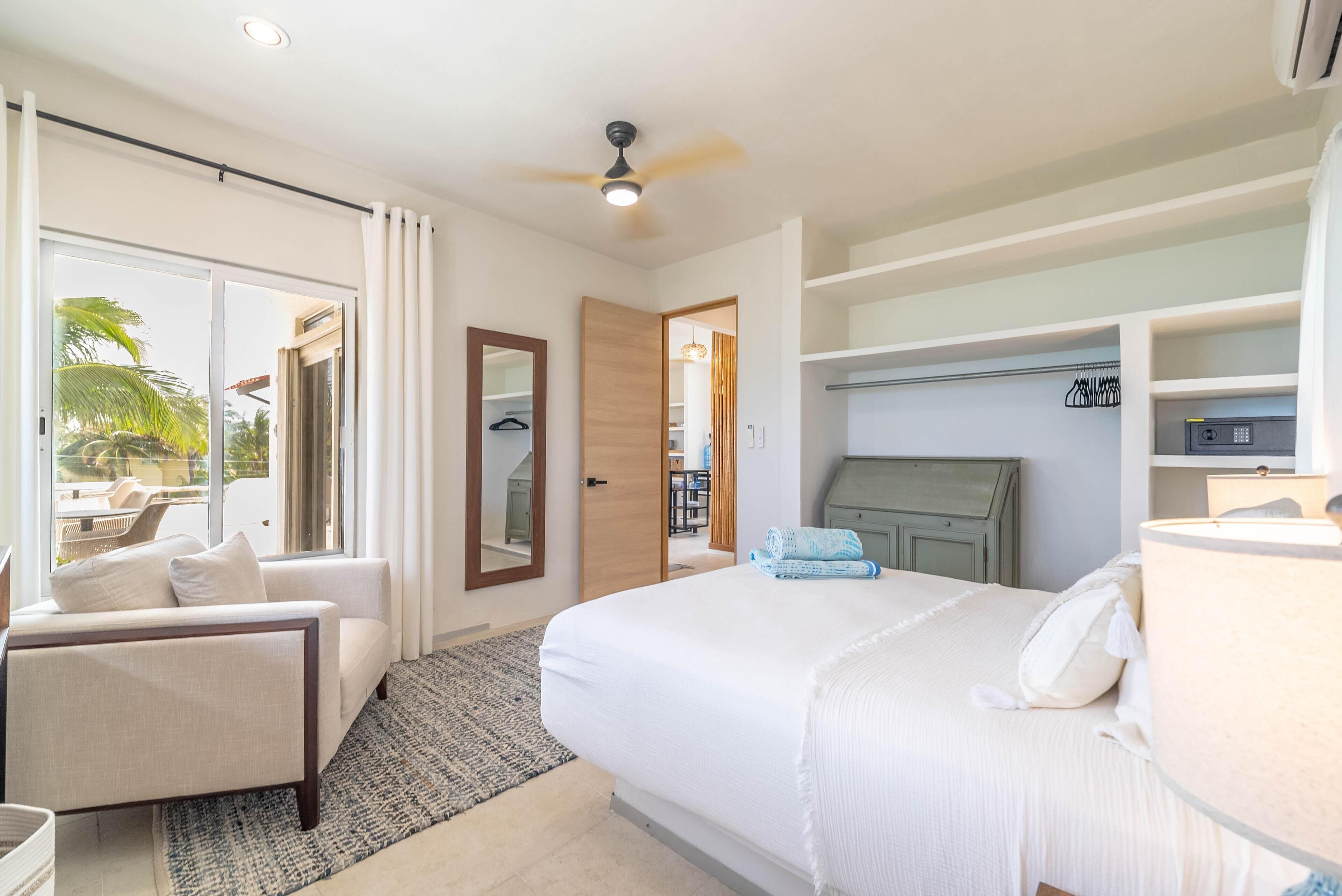 A hotel room with a bed, a chair, a desk, and a wardrobe.