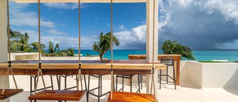 A wooden swing set with a view of the ocean and palm trees.