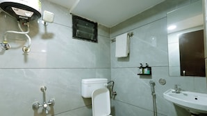 Une salle de bain équipée de toilettes, d’un bidet, d’un lavabo et d’un miroir.
