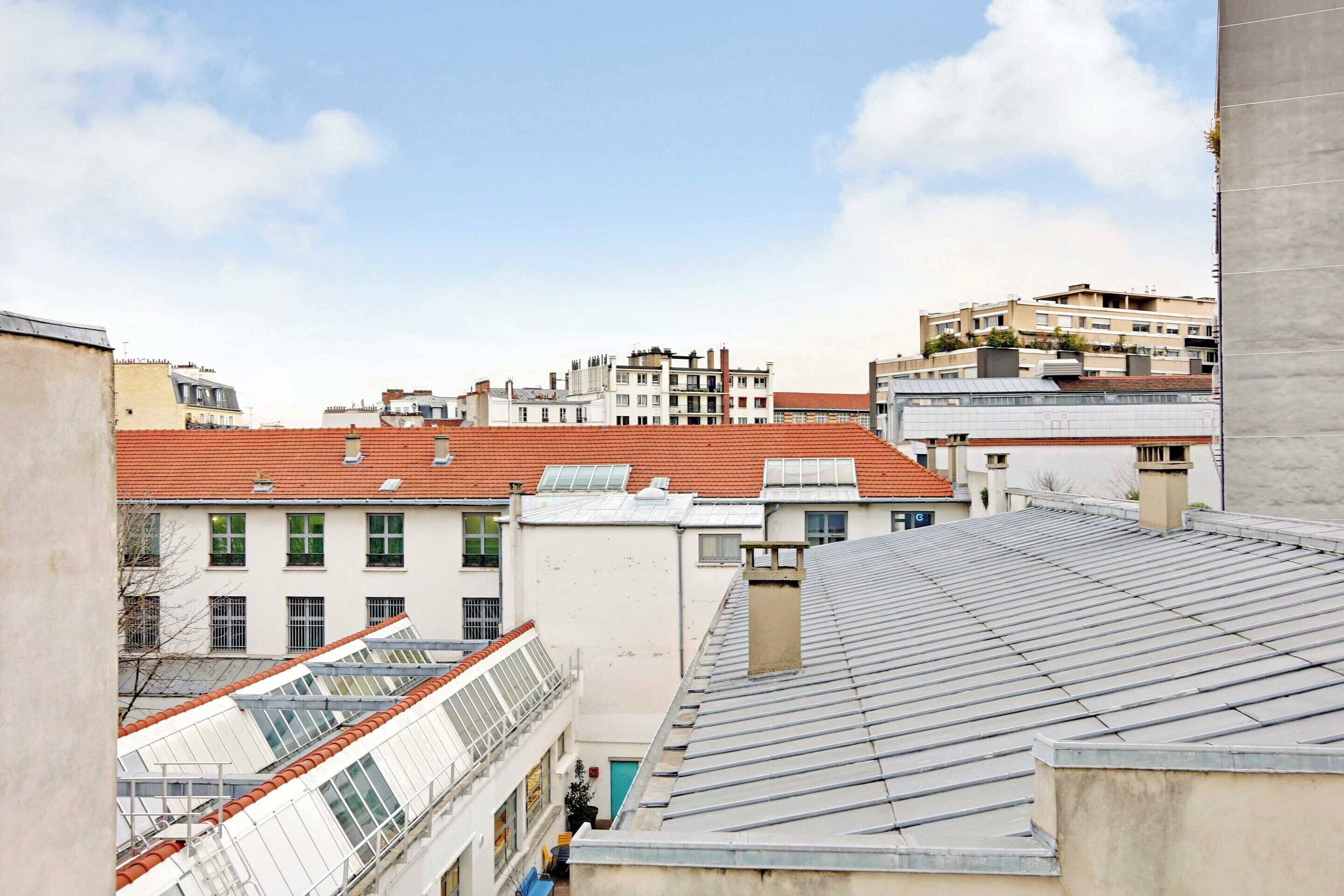 Vista de una zona residencial con varios edificios, incluyendo uno con tejado rojo y otro con tejado gris.
