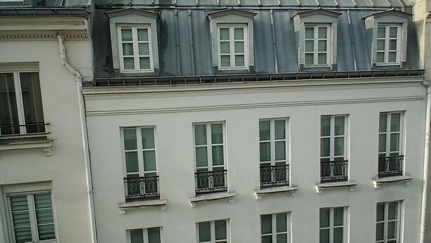 A multi-story building with a symmetrical facade, featuring evenly spaced windows and balconies. - Le Marais St.Paul Mobility lease apartment  (Paris)