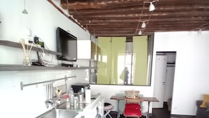 A modern kitchen with a built-in stove, a washing machine, and a dining area with a table and chairs. - Le Marais St.Paul Mobility lease apartment  (Paris)